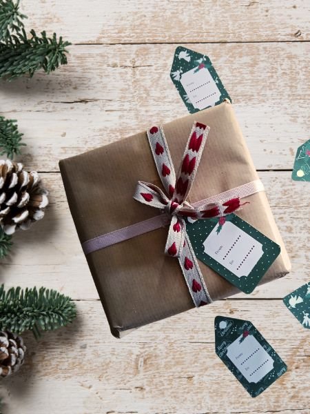 a gift wrapped in brown paper with a ribbon and tags on a white wood surface